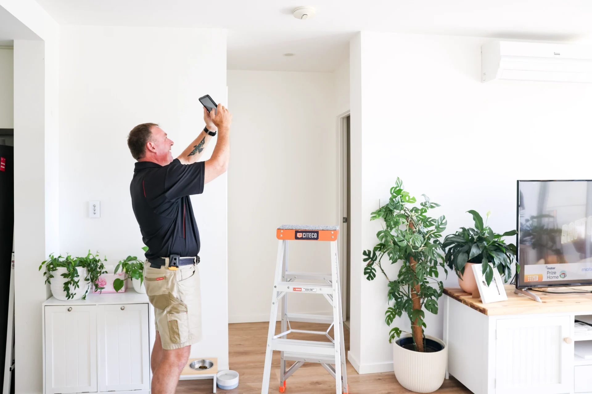technician-testing-residential-smoke-detector-with-tablet